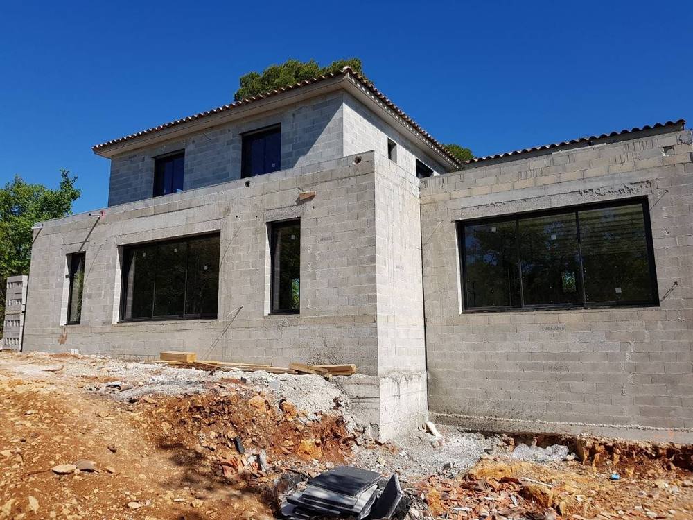 Structure d'une maison en construction : murs en parpaings et ouvertures